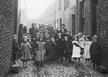 Group of children in an alley in 19th century Belfast, many barefoot.