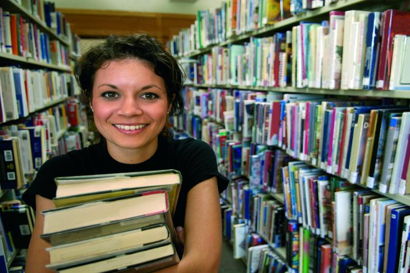 Girl carrying bundle of books in the Library