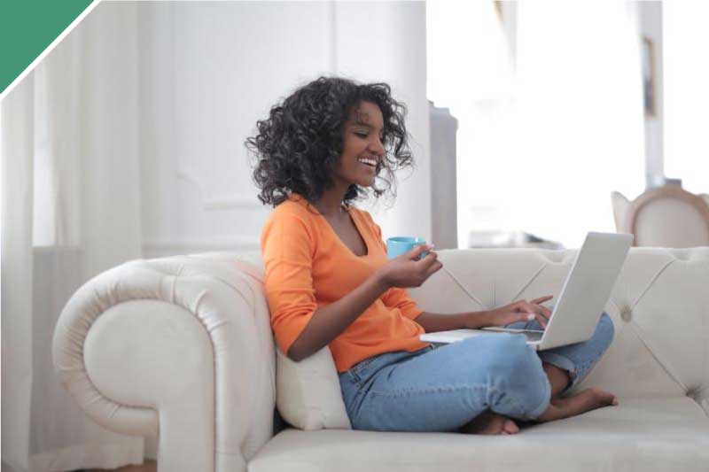 Woman sitting on sofa with laptop