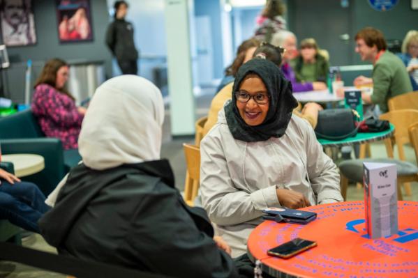 Two females talking in the QFT over a red table