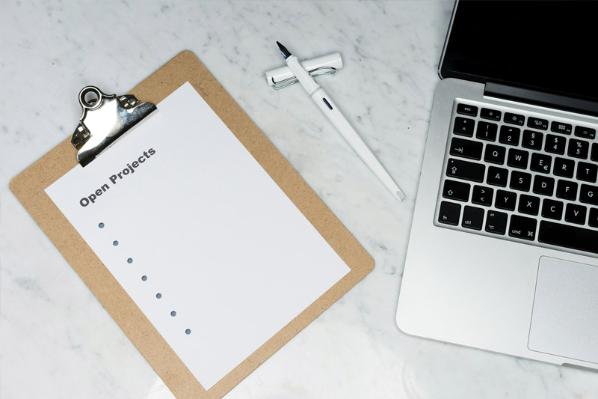 A desk containing a laptop and a clipboard with a sheet titled Open Projects