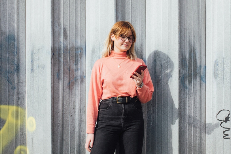 Standing female student scrolling through phone
