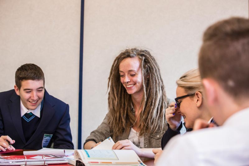 A student volunteer from the Queen's Univeristy Belfast Homework club helping school pupils with their homework