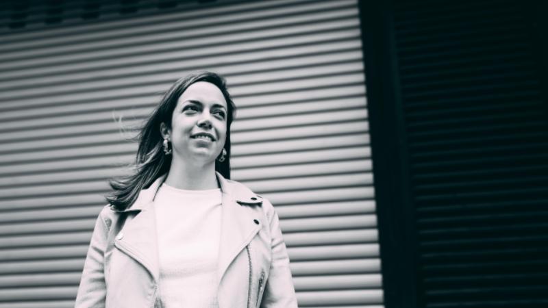 A person standing in front of a shop shutter smiling as they look off camera