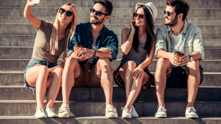 students sitting together in the sun taking a selfie photo