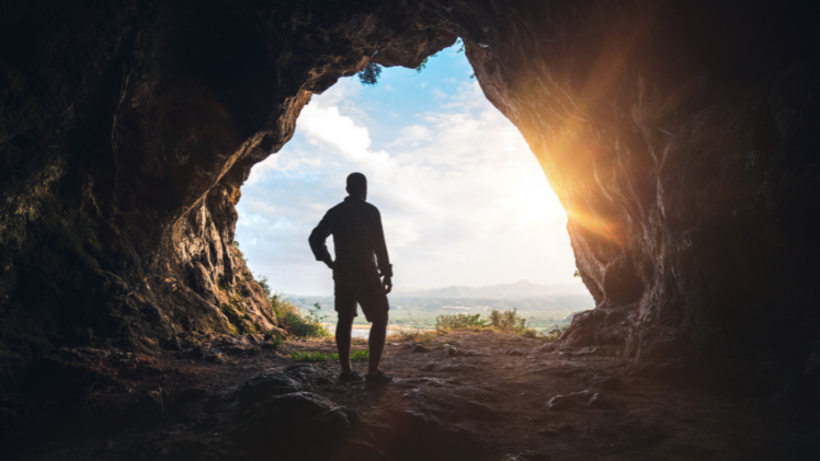 man standing at exit of a cave