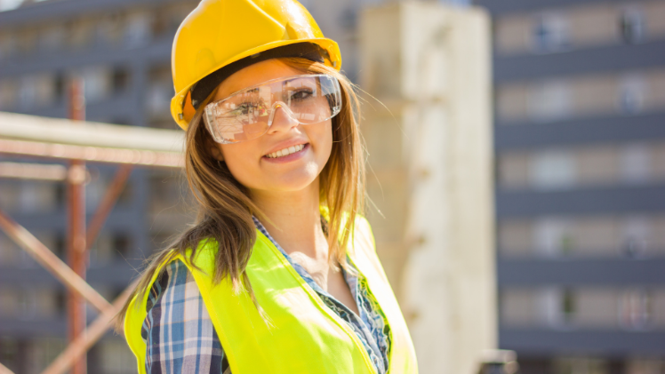 a female construction worker smiling at camera wearing a hard hat