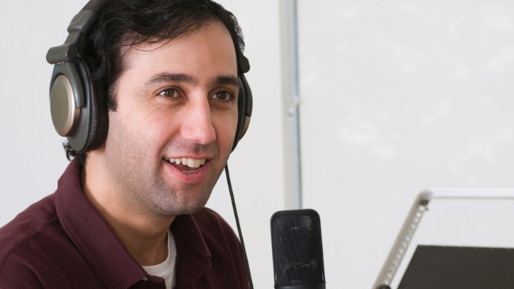 male sitting with headphones on in front of a podcast mic