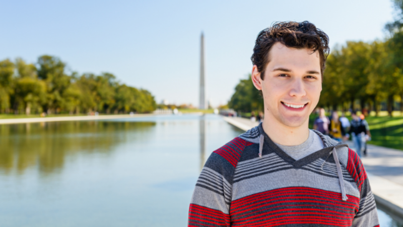 student standing alone outside smiling on a clear day