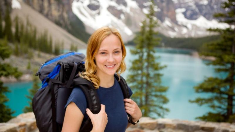 student standing with a backpack on at a lake