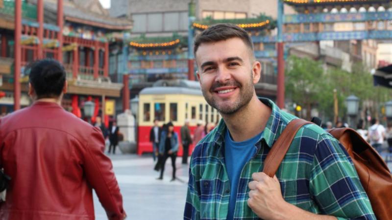 male student standing holding a backpack in Asia