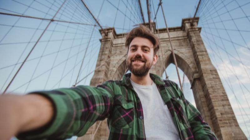 student standing on a bridge smiling to camera