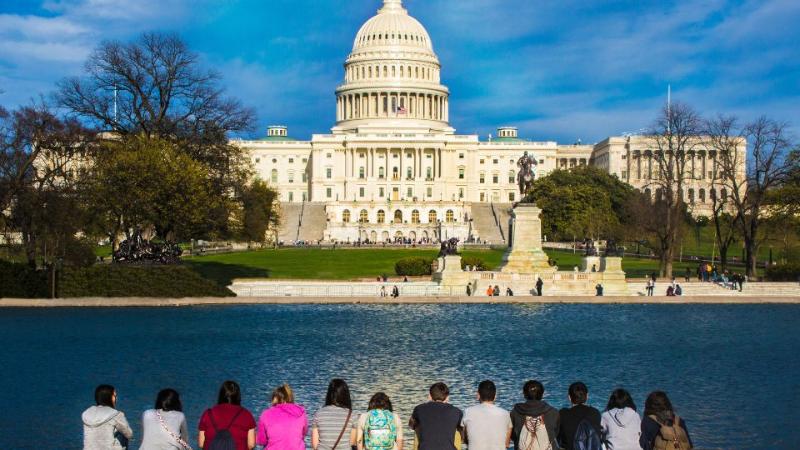 students sitting in a row with their backs to camera looking at the Whitehouse in Washington