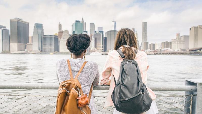 two female students standing on a bridge with their backs to the camera looking at view