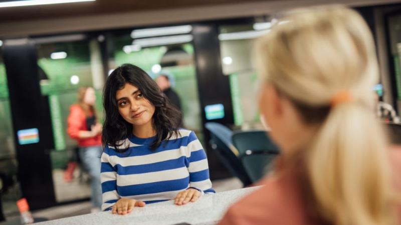 female students standing at information desk