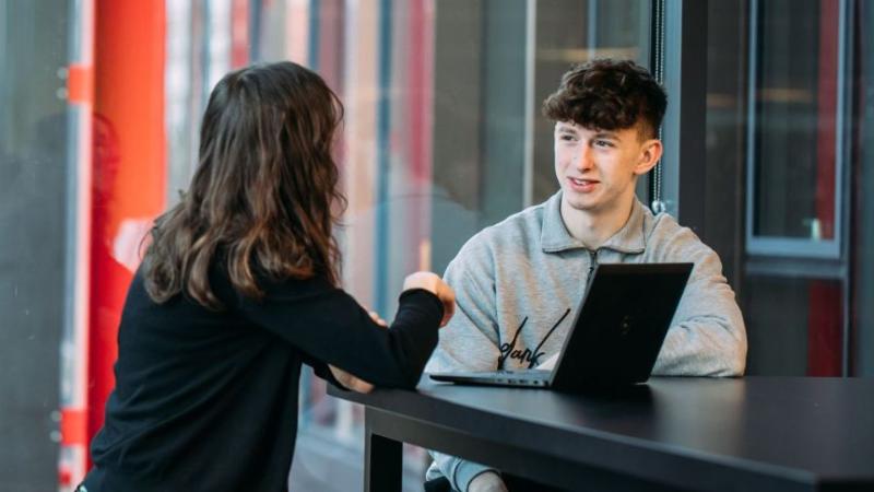 student sitting talking to a staff member