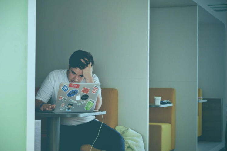 stressed student sitting in a booth with a laptop
