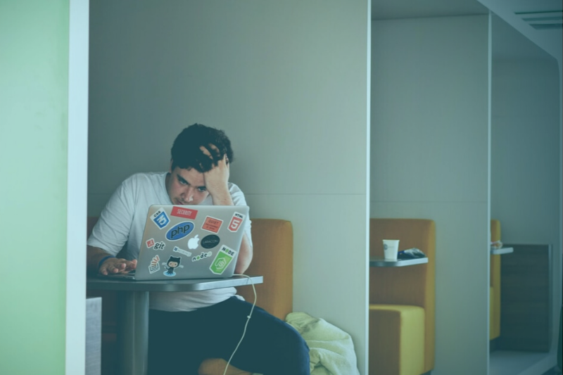 stressed student sitting in a booth with a laptop