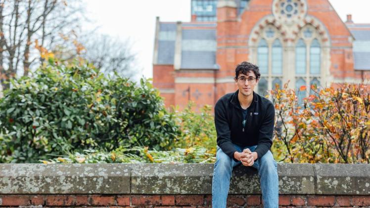 Student sitting on the wall in front of the Graduate School