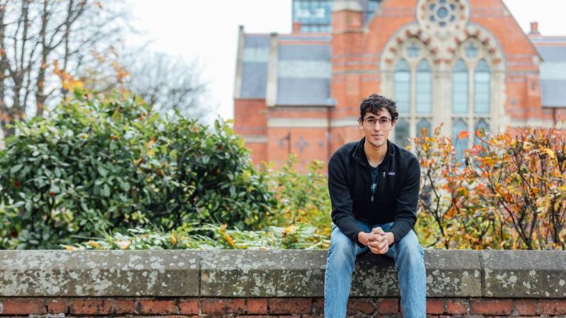 Student sitting on the wall in front of the Graduate School