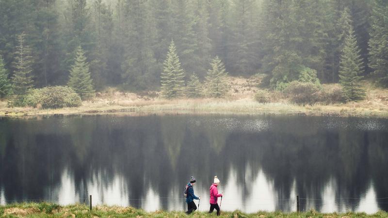 Two people walking by a lake