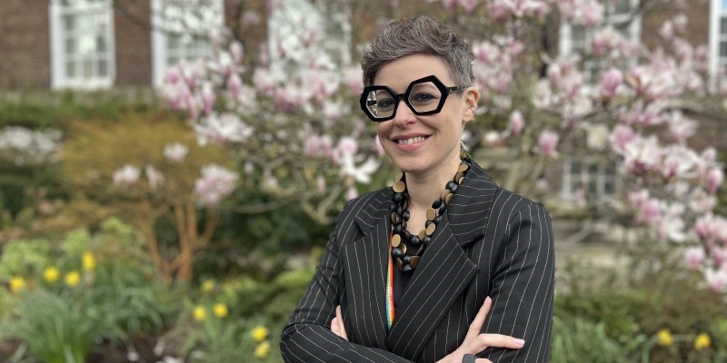 Portrait of Dr Federica Ferrieri, with bold glasses, by a tree in blossom