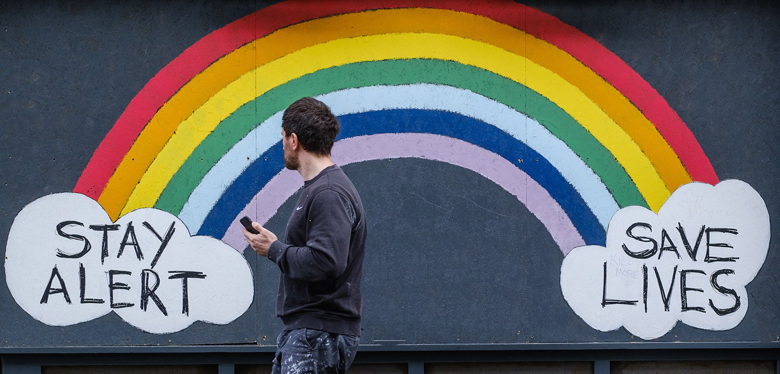 Man walking past a painted rainbow