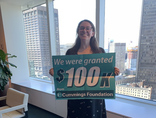 Woman holds a fundraising sign for 100k