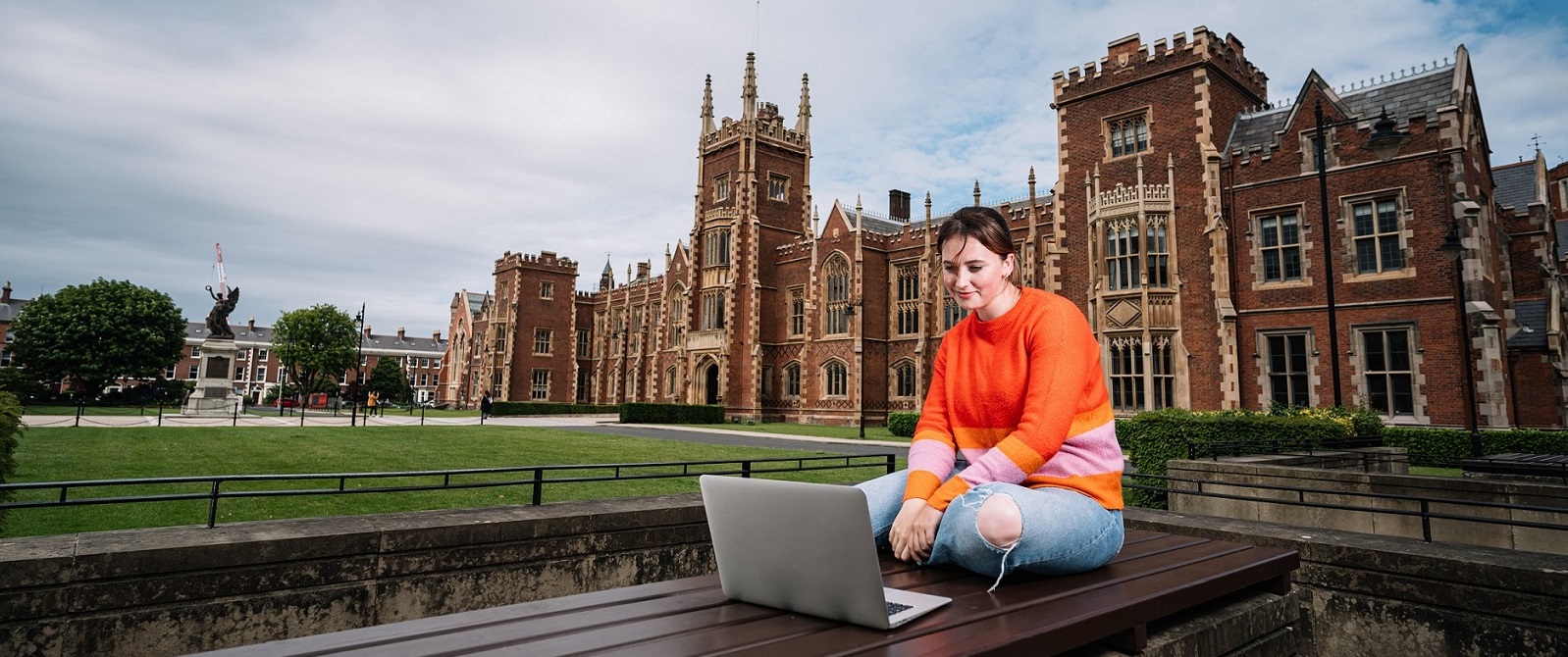 Student at laptop in front of building