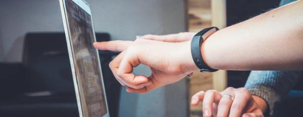 Two hands pointing at a laptop