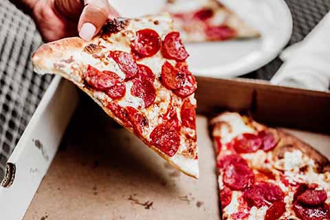 Person lifting a slice of pizza