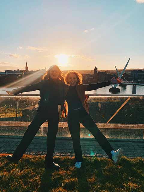 Students pose in Derry with the sunset behind them