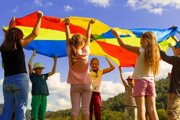 Children playing under a rainbow coloured sheet