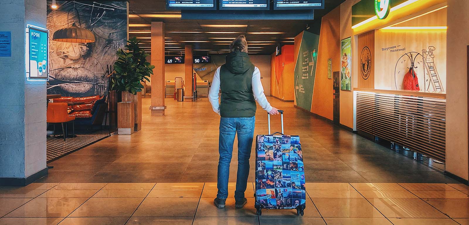 Person in the airport with a wheelie suitcase looking at a board