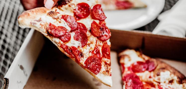 Pizza slice being lifted out of a box