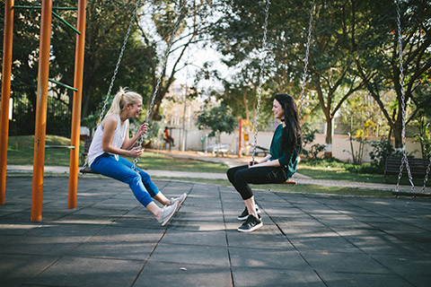 Two girls on swings chatting
