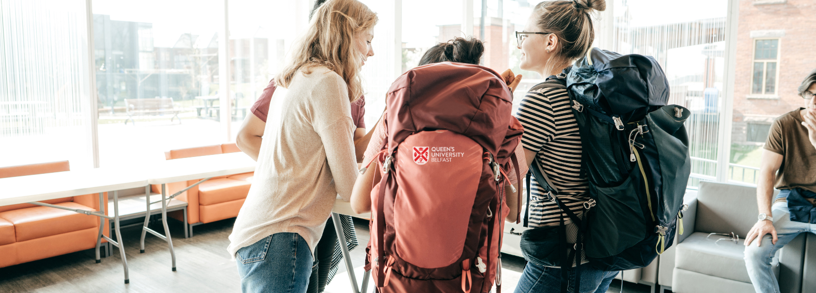 three students with backpacks around a table