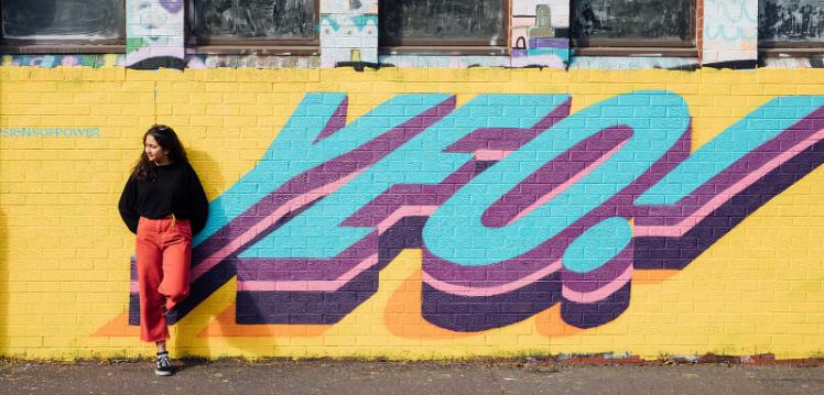 Student standing at Yeo graffitti