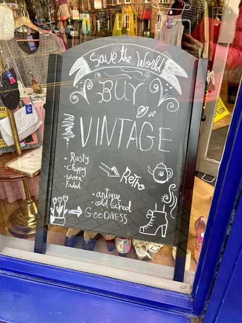 Shop sign saying save the world buy vintage