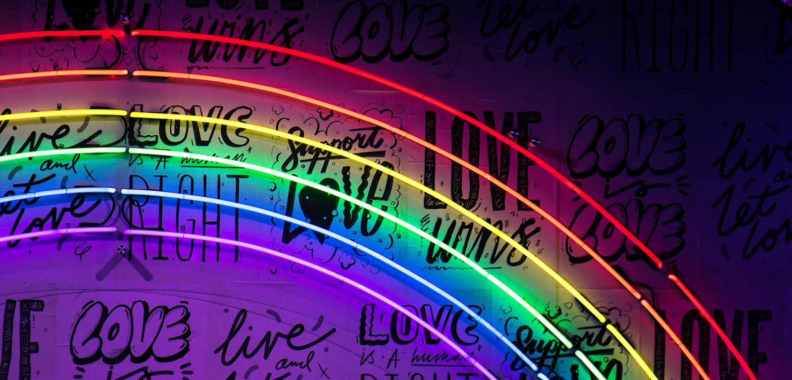 neon rainbow with the words love is love behind it