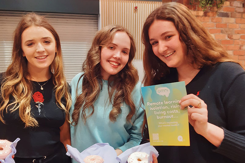 Students with donuts and an omni poster