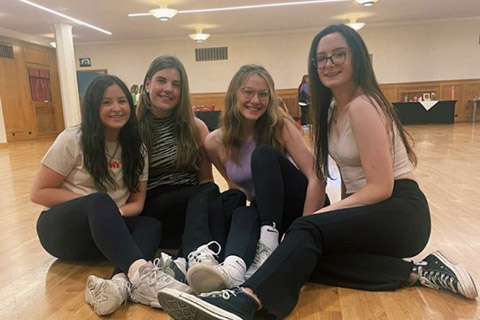 Group of students sitting on a wooden floor