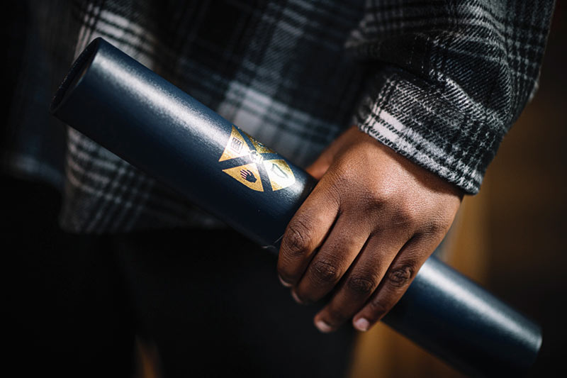 Student's hand holding a scroll holder