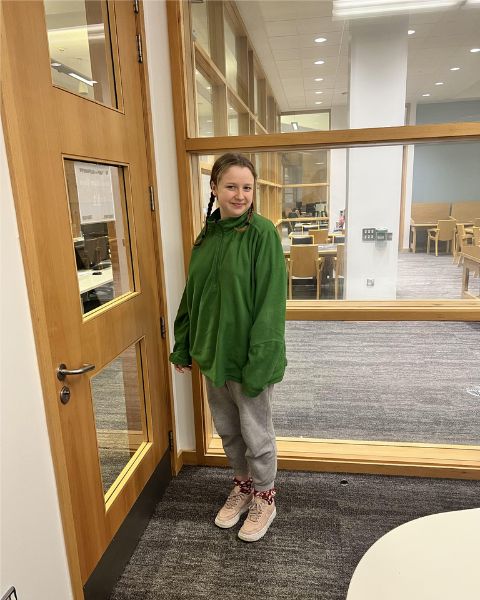 Niamh wearing a green fleece in the library
