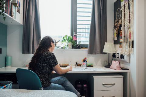 Student writing on table in accommodation