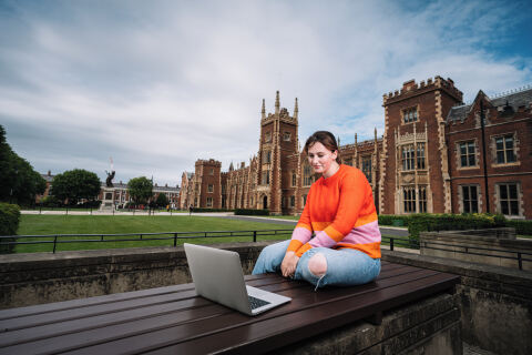 Student on laptop in front of Lanyon