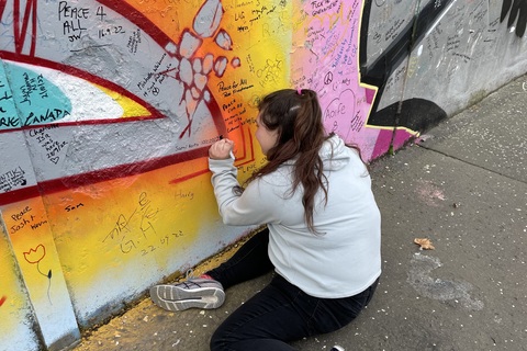 Student signing peace wall