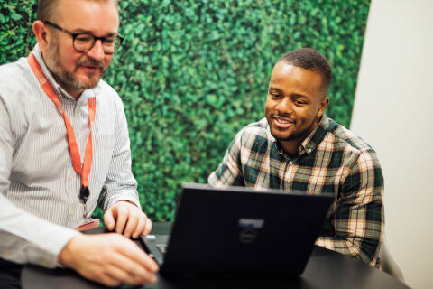 Student and staff member sitting together in front of laptop