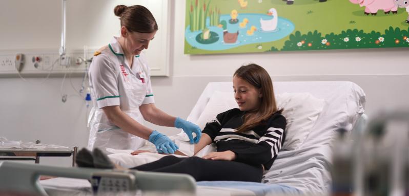 Nursing student performing assessment on female child in hospital style setting