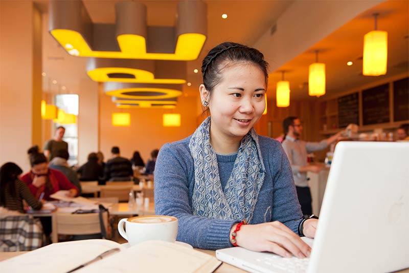 female international student using laptop in Hope coffee shop